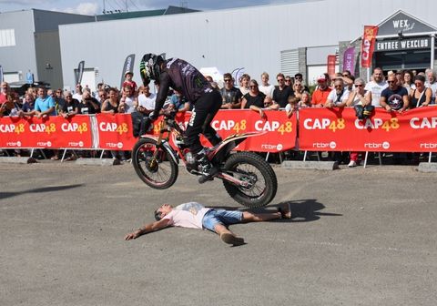 Acrobate sur sa moto-cross effectuant un saut au-dessus d'une personne allongée. Performance réalisée à l'occasion de l'événement rando moto de CAP48 & Classic 21