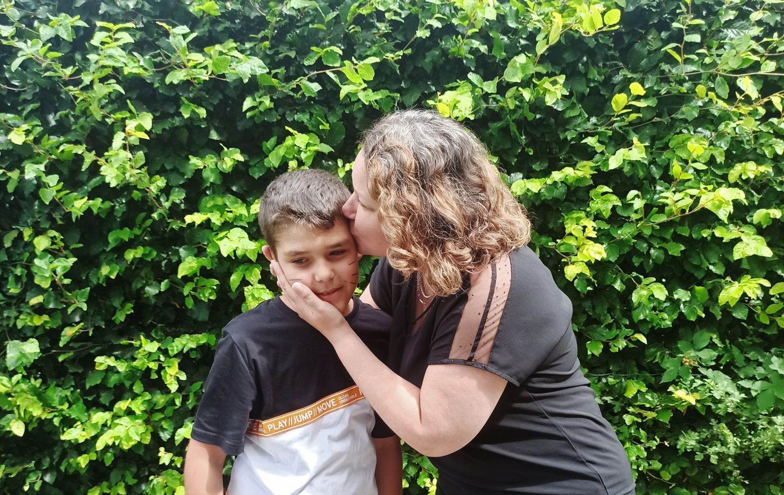 Portrait d'une maman embrassant sur la tempe son fils Florian, atteint d'autisme