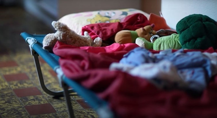 Photo d'un lit parapluie avec des jouets d'enfant pour illustrer l'aide de relogement apportée via le fonds d'urgence de CAP48 suite aux inondations