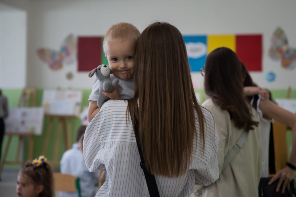 Portrait d'un jeune enfant dans les bras d'une adulte vue de dos pour illustrer l'aide d'urgence sociale à destination des réfugiés ukrainiens initiée par CAP48
